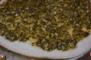 Pesto sauce added to pizza crust.