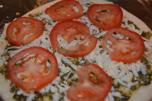 Tomato layer on pesto pizza.