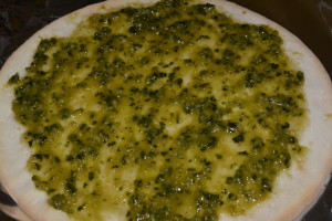Pesto sauce layered onto pizza crust.