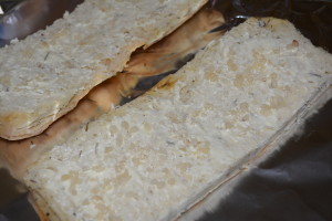 Cut focaccia in half lengthwise and spread butter with minced garlic on top.